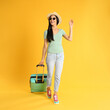 © New Africa - Beautiful woman with suitcase for summer trip on yellow background. Vacation travel