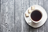 Fototapeta Mapy - White cup with coffee on a white saucer on a gray wood background