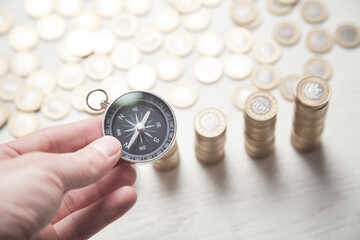 Wall Mural - Male hand showing compass. Coins on the white desk