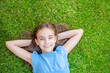 © Ermolaev Alexandr - Smiling teen girl lying on a grass, top down view