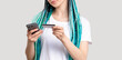 © golubovy - Z generation woman with blue colored hair braids. Hipster lady with ethnic hairstyle using credit card phone for banking operation unrecognizable isolated on white. Cashless payment. Online booking.