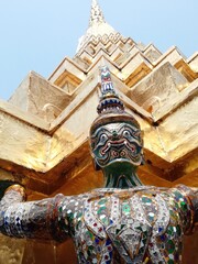 Monkey and demon supporting a Golden Chedi at the Temple of Emerald Buddha.