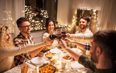 Poster - holidays, celebration and people concept - happy friends having christmas dinner at home drinking non-alcoholic red wine