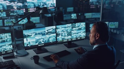 Fototapete - Male Officer Works on a Computer with Surveillance CCTV Video Footage in a Harbour Monitoring Center with Multiple Cameras on a Big Digital Screen. Employees Sit in Front of Displays with Big Data.