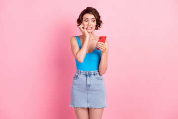 Poster - Photo of cute pretty young horrified girl hold telephone bite finger read feed corona virus kill more people world last week wear denim mini skirt blue singlet isolated pink color background