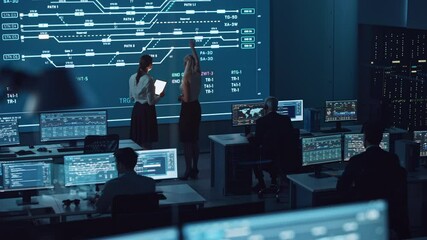 Poster - Two Software Engineers Talking Next to a Big Screen in a Modern Monitoring Office with Live Analysis Feed with Charts. Monitoring Room Big Data Scientists and Managers Sit in Front of Computers.