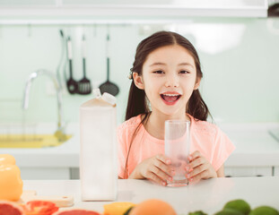 Wall Mural - Cute little girl drinking with milk at kitchen