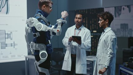 Poster - In Robotics Development Laboratory: Engineers and Scientists Work on a Bionics Exoskeleton Prototype with Person Testing it. Designing Wearable Exosuit to Help Disabled People. Slow Motion
