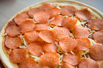 Pizza with pepperoni before cooking on the kitchen table.