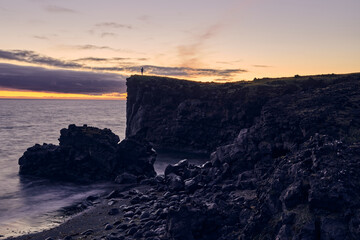 Iconic view of man on top of the hill at a sunset on the west coast of Iceland