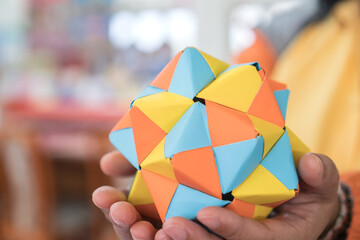 multicolor modular origami star sphericalal of modular origami spiky ball model on student hand, decoration visual art on geometry paper folding and difficult level skills in study at school