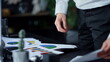 © stockbusters - Businessman holding reports on paper in office. Entrepreneur standing at table