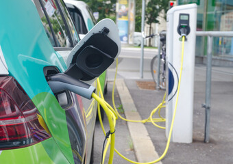 Modern electric cars plugged in charging on the street station. New energy vehicles, environment friendly alternative energy for cars