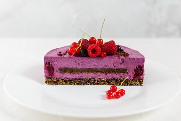 Mousse cashew cake with black currant and chocolate praline in a cut. Sugar, lactose, gluten free. Vegan dessert, healthy food.