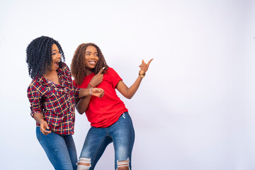 two beautiful young black women feeling excited and happy and pointing to the space to their side. a