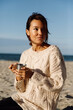 © Danil Nevsky/Stocksy - Young woman drinking tea on seashore