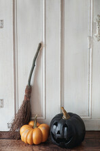 Pumpkins And Broom Against White Door