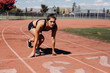 © Leah Flores/Stocksy - Woman Starting to Run on Track