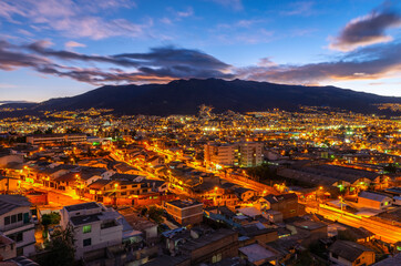 Wall Mural - The skyline of Quito at sunset with night lights with the Pichincha volcano, Ecuador.