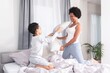 © focusandblur - Playful mother and son fighting with pillow on bed