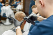 © Svitlana - Serving client. Young man visiting barbershop and getting new trendy haircut. Barber working with hair clipper. Focus on a head