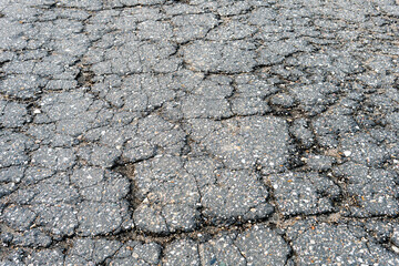 Fragment of a russian countryside road with a cracked asphalt. Old broken asphalt texture