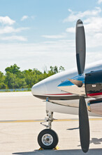 Front View, Close Distance Of The Nose And Propeller Of A Commercial, Twin Engine, Airplane Getting Ready To Take Off From A Tropical Airport