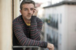 © TheVisualsYouNeed - urban lifestyle emotional portrait of 40s handsome man sad and depressed at home balcony leaning upset feeling worried suffering depression problem looking to city street