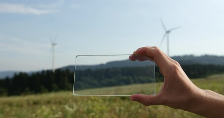 Hand architect or Engineer using smartphone transparent hologram digital display on the background of a wind turbine Technology, people.