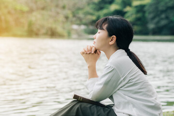 Wall Mural - Woman praying in the morning on nature background.Hands folded in prayer on a Holy Bible in church concept for faith, spirituality and religion