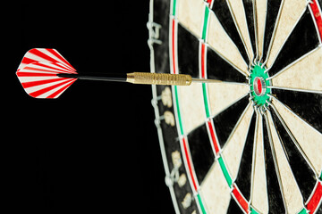 Darts on a black background. 1 dart flies directly to the center of the target. Business center goal concept