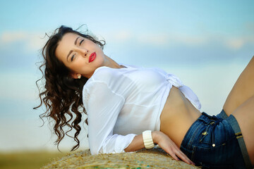 attractive girl in white shirt and shorts posing in the summer in the field