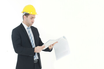 Handsome and smart engineer in black suit Wearing a yellow safety engineer hat with hand holding Construction drawing papers and serious in work isolated on yellow background. Copy Space