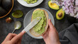 Avocado toast. Woman's hands spreading avocado pasta on bread slice. Healthy food concept.