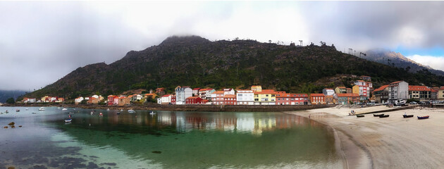 Wall Mural - Foggy panoramic view of the colorful village of O Pindo in the Atlantic ocean coast of Galicia, in northwestern Spain.