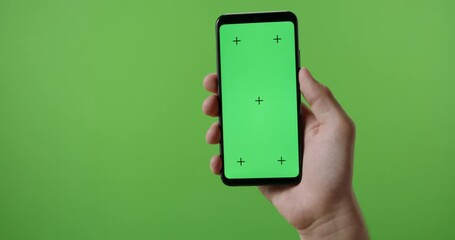 hands of man holding a phone with vertical green chroma key screen. isolated on green background, sw