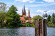 View to blurred shore of Werder, Havel, with Holy Spirit Church -Heilig Geist Kirche-, in the foreground a seagull on an iron post