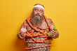 © wayhome.studio  - Photo of obese European man has good appetite, holds sweet delicious doughnut and dumbbell, has intensive workout for keeping fit, wrapped by sausages, eats too much, leads unhealthy lifestyle