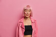 © wayhome.studio  - Portrait of pleased young Asian woman licks lips, stands with closed eyes, remembers pleasant taste of something, wears black top and pink jacket, poses against rosy background, feels satisfied