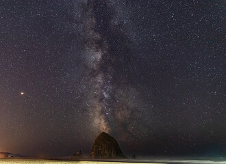 Wall Mural - Milky Way galaxy shines in the sky behind Haystack Rock on Cannon Beach in Oregon