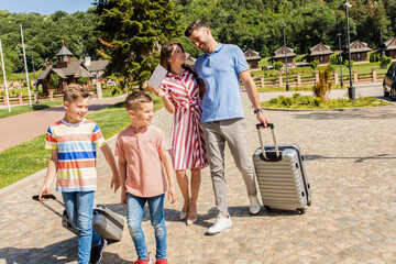 Wall Mural - smiling family of four going to the hotel to check in at the reception for vacation.
