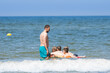 Mężczyzna pilnuje dzieci pływających na dmuchanym materacu w morzu