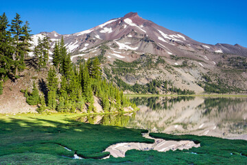 Wall Mural - volcanic mountain landscape with clear blue sky, morning light, and reflective water in the foregrou