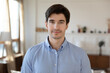 © fizkes - Portrait of smiling young handsome man freelancer standing in modern living room. Happy millennial bearded guy homeowner looking at camera, posing at home, social network profile picture concept.