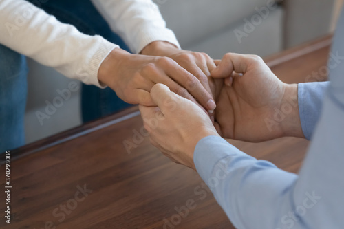 Close up young man sitting in front of beloved woman, stroking hand showing support in difficult life situation or apologizing for conflict. Loving affectionate couple enjoying sincere conversation.