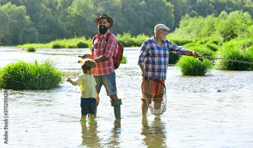 Man in different ages. Fishing. Grandpa and grandson are fly fishing on river. Man teaching kids how to fish in river.