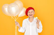 © Anatoliy Karlyuk - Colorful isolated image of overjoyed ecstatic middle aged European woman wearing white blouse and red beret laughing, having fun, holding helium balloons, eating macaron, being in good mood