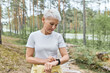 © Anatoliy Karlyuk - Active mature woman with short blonde hair posing outdoors, getting ready for jogging exercise, setting smart watch, tracking heart rate and pulse. People, sports, fitness and technology concept