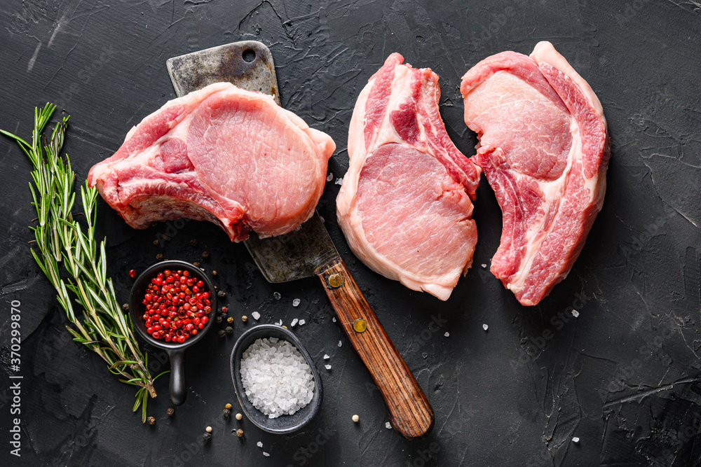 Organic  Pork meat chop  set over american classic butcher knife or cleaver with spices and rosemary and red pepper on black slate table top view. - obrazy, fototapety, plakaty 