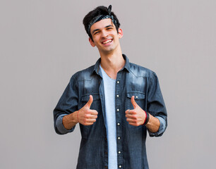 Wall Mural - Happy successful confident man showing thumbs up. Handsome young man gesturing and keeping mouth open while standing against gray background